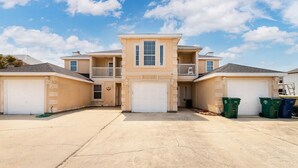 A two-story residential building with a central entrance, two garages, and a balcony. - Island Townhouse w/ Private Hot Tub! (Corpus Christi)