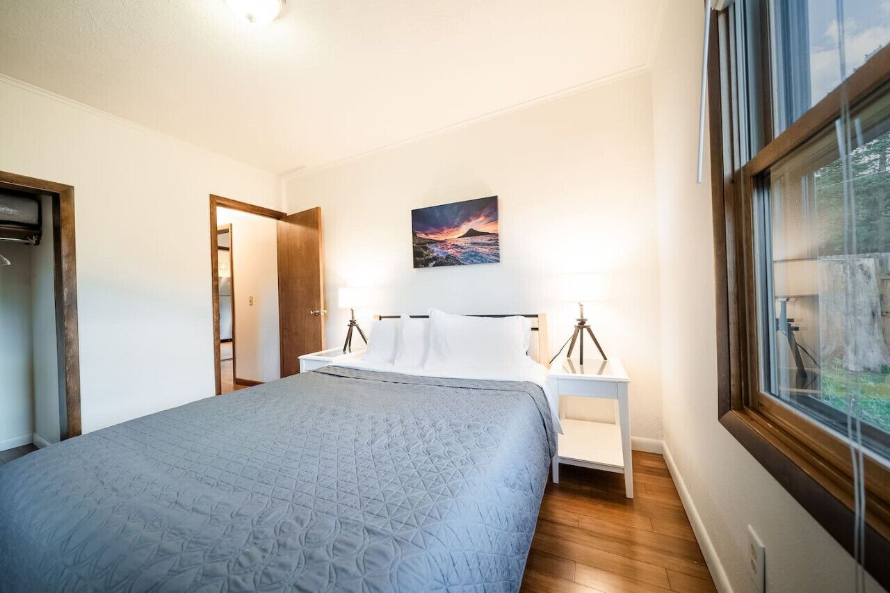Ein Schlafzimmer mit Bett, Nachttischen, einem Gemälde und einem Fenster.
