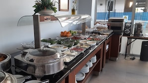 A buffet setup with various food items, a coffee machine, and a potted plant. - Batu Pansiyon (Denizli)