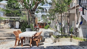 A courtyard with a stone table and chairs, surrounded by buildings with balconies and a reception sign. - Batu Pansiyon (Denizli)