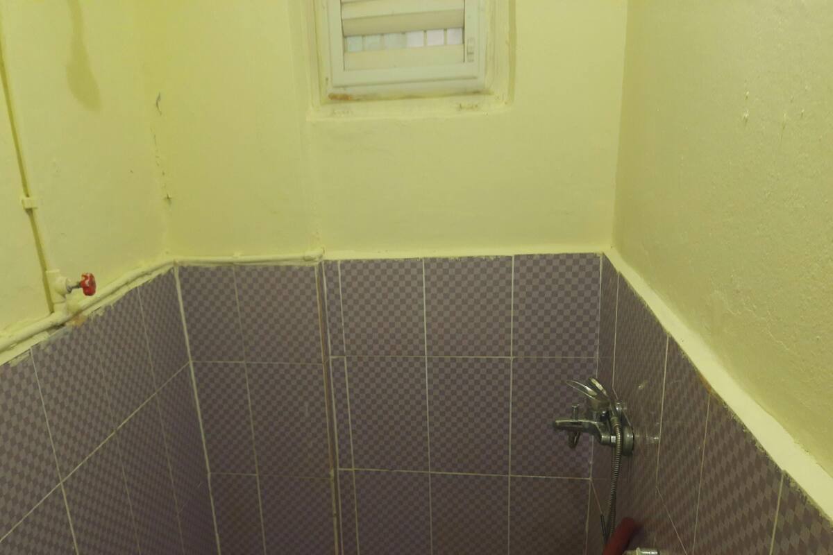 Een badkamer met zwart-witte betegeling, een douche en een raam met een witte omlijsting.