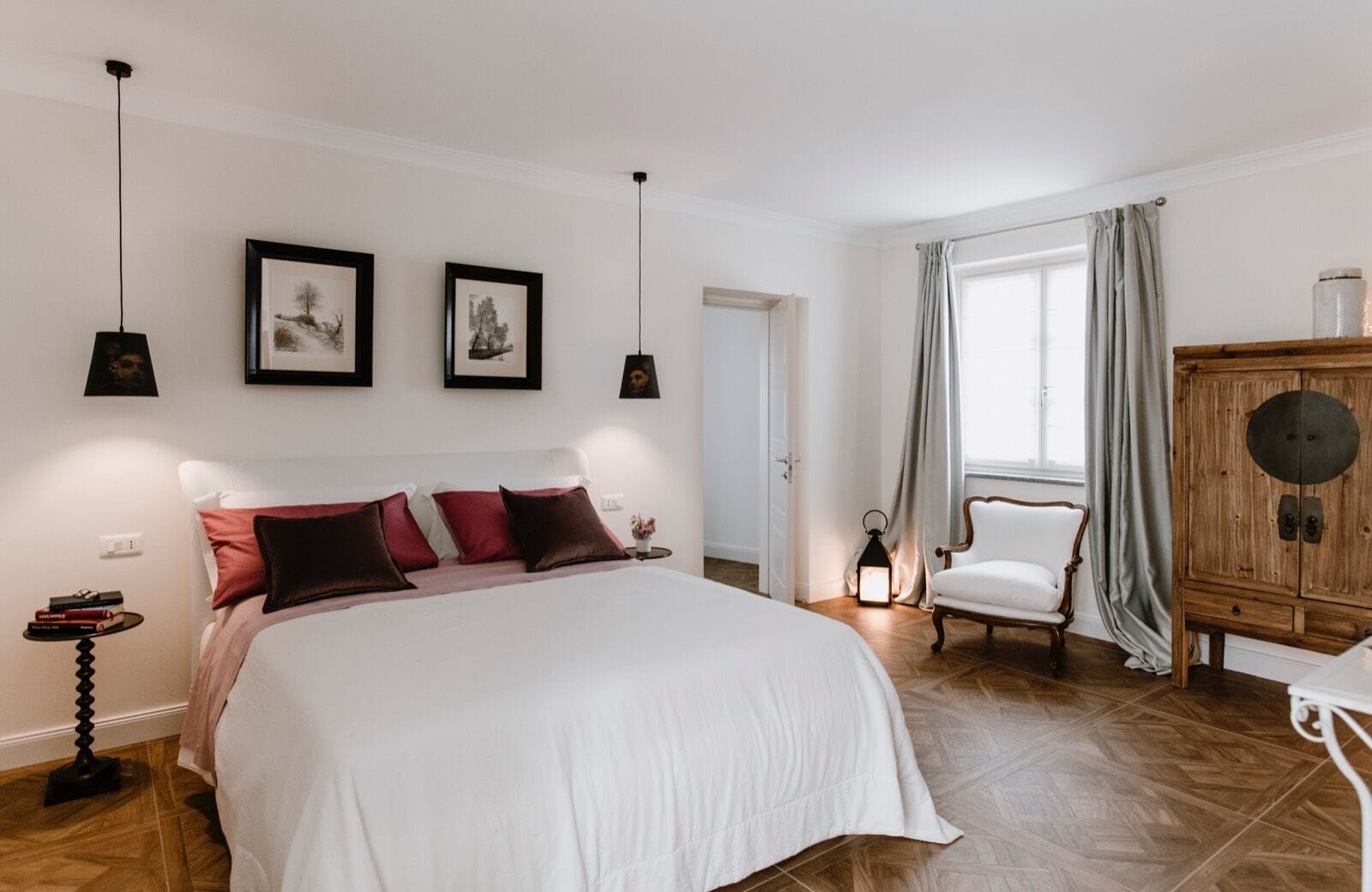 Une chambre à coucher avec un grand lit, une armoire en bois, une chaise et une table de chevet avec des livres.