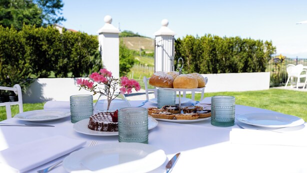 A table set for a meal with plates, cutlery, and a variety of desserts.