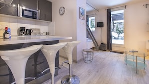 A modern kitchen with a bar area, a clock, and a staircase leading to a balcony. - Perfect for couples, friends and small families. (Chamonix-Mont-Blanc)