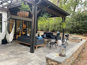 An outdoor patio with a hammock, a sofa, a grill, and a lantern.