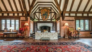 A room with exposed wooden beams, a fireplace, and patterned rugs. - Historic Traditional Estate - Heated Pool - Every Amenity (East Hampton)