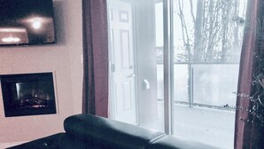 Een woonkamer met een zwarte leren bank, een vastgehangen flatscreen-televisie en een ingelijst schilderij aan de muur.