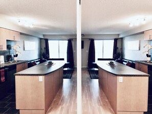 Enjoy cooking in this well-equipped kitchen with a central island, wooden cabinets, and a large window.