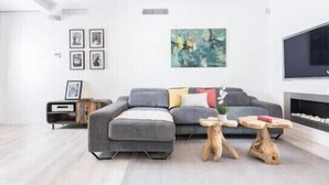 A modern living room with a grey sectional sofa, a coffee table, and a TV mounted on the wall. - innSevilla luxury apartment pilatos, comfort and luxury in this apartment (Sevilla)