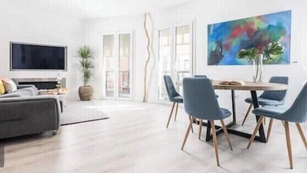 A modern living room with a grey sofa, a flat-screen TV, a dining area with a table and chairs, and a large abstract painting on the wall. - innSevilla luxury apartment pilatos, comfort and luxury in this apartment (Sevilla)