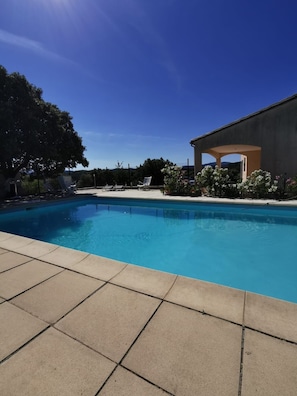 Una piscina con sillas de descanso, un porche techado y vistas del paisaje circundante.
