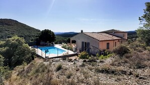 Una casa con piscina, rodeada de colinas y árboles.