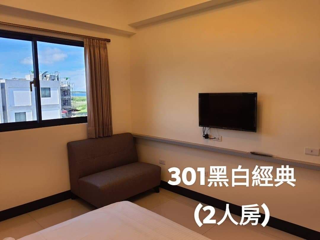 A 2-bedroom apartment with a large window, a flat-screen TV, and a brown sofa.