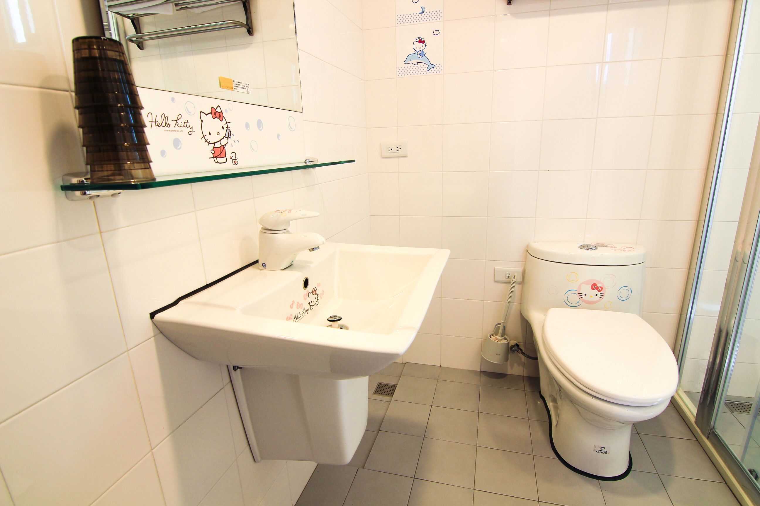 Een badkamer met een wit wastafelmeubel, toilet en een douchecabine met glazen wanden.