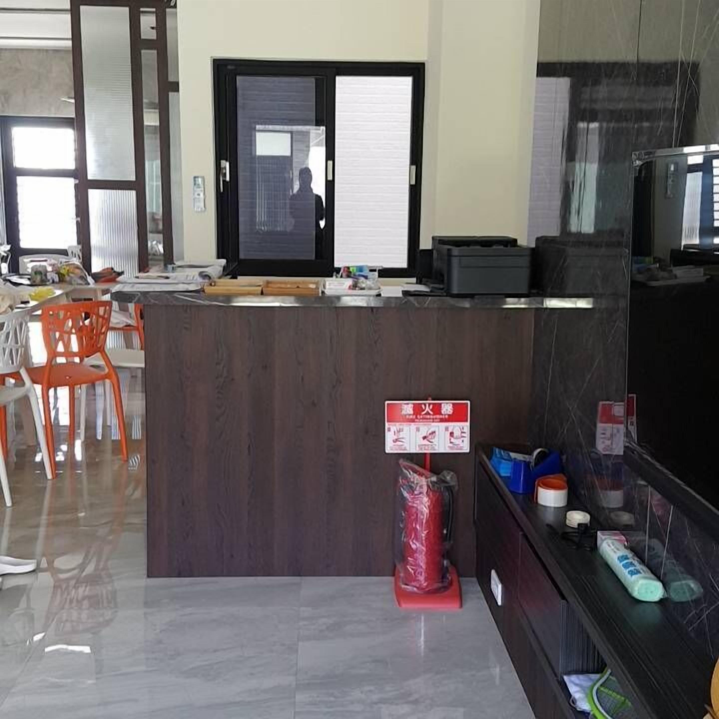 A reception desk with a computer, a sign with emergency instructions, and a trash bin.