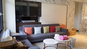 Una sala de estar moderna con un sofá seccional gris, una mesa de centro redonda y un televisor montado en la pared.