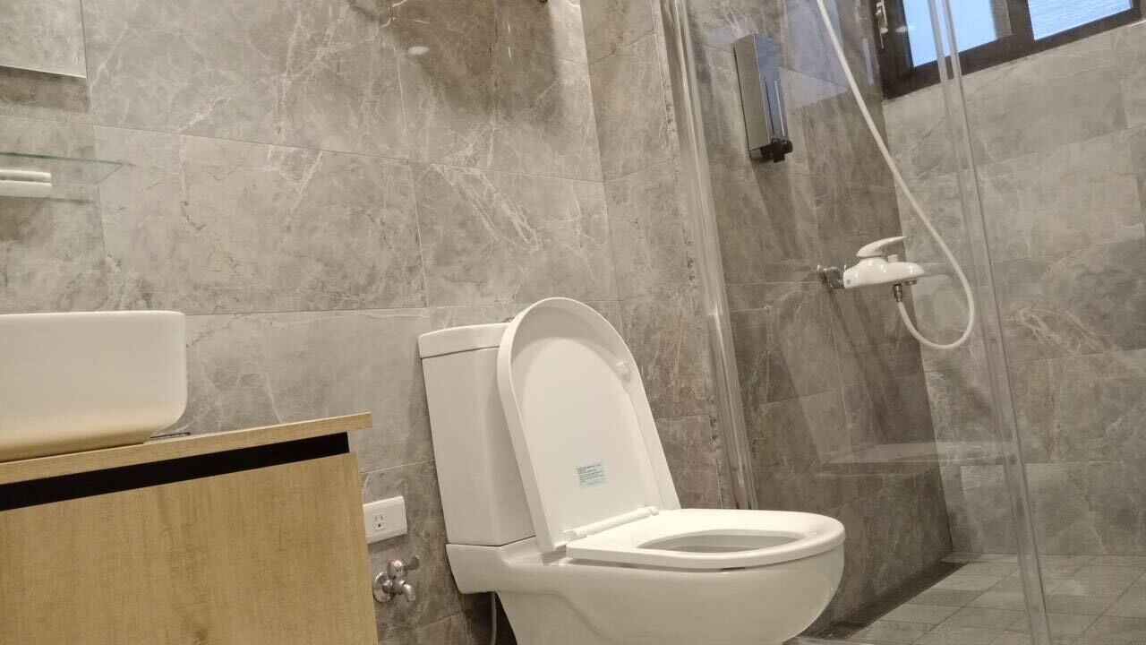 A modern bathroom with a toilet, shower, and marble walls.