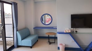 Una habitación con un sofá, una pequeña mesa redonda, un televisor y un espejo en la pared.