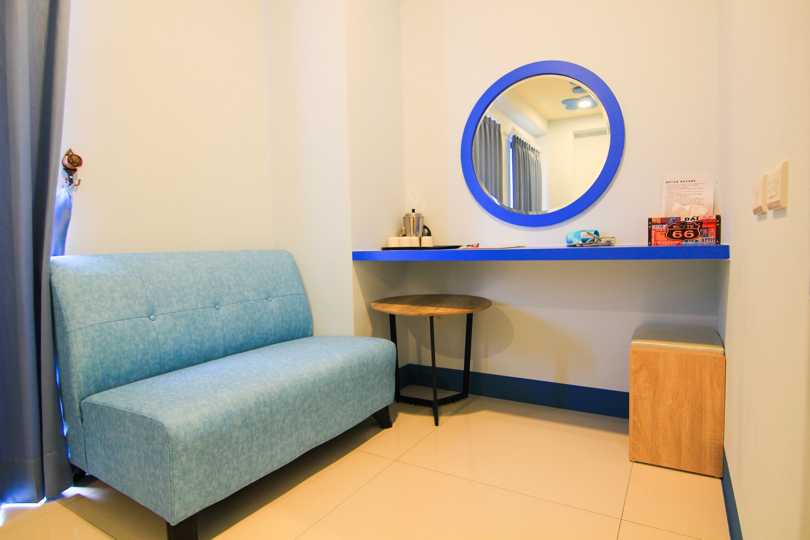A room with a blue sofa, a small round table, a mirror, and a wooden cabinet.