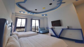 Habitación de hotel con un mural grande de Hello Kitty en el techo, dos camas, un televisor y un escritorio con una silla.