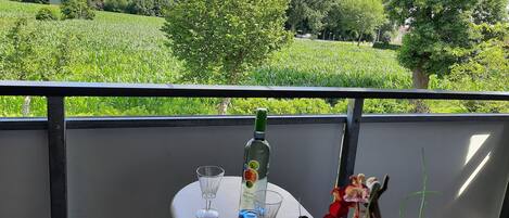 Ein Balkon mit Tisch, einer Flasche und einem Glas.