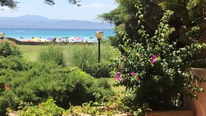 A covered outdoor seating area with a view of a beach and mountains.