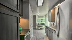 A narrow kitchen with dark cabinetry, a stainless steel refrigerator, and a microwave on a white countertop. - Cozy 4 Bedroom Home 1.1 Mile to Market Square! Late Sunday Checkouts No Problem! (Fredericksburg)