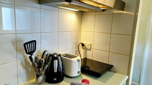 A kitchen with white tiles, a stainless steel sink, a toaster, a kettle, and a spatula. - studio on  Swanston st apartment with a little English flare (Carlton)