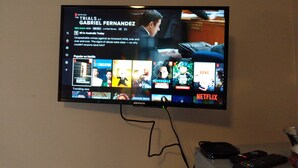 A television mounted on a wall displaying a Netflix interface with various shows and movies. - studio on  Swanston st apartment with a little English flare (Carlton)