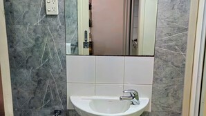 A bathroom with a white sink, a mirror above it, and a marble-patterned wall. - studio on  Swanston st apartment with a little English flare (Carlton)