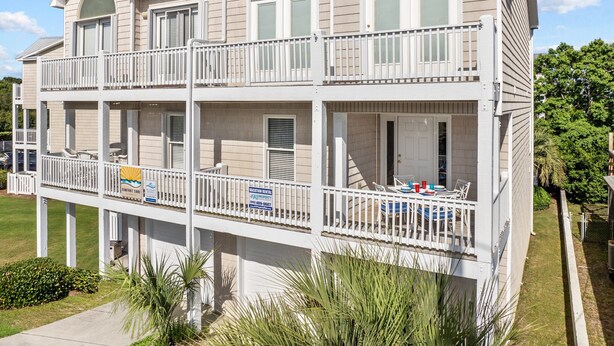 A two-story vacation rental with a balcony, a sign indicating it's a vacation rental, and a contact number. - Andreas Place Spacious Family Getaway, Easy Beach Access, Pool (Kure Beach)