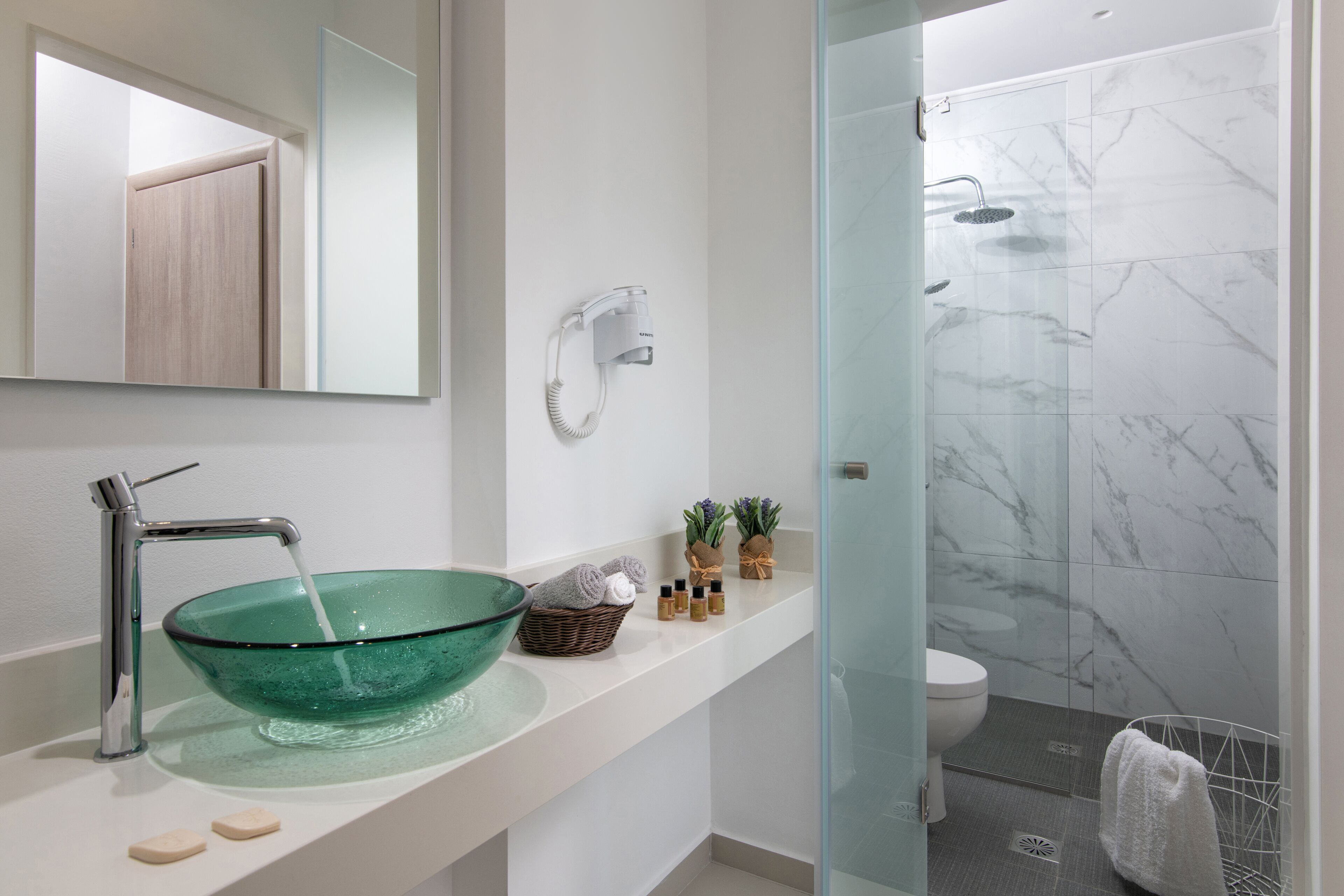 A modern bathroom with a glass bowl sink, a handheld showerhead, and a toilet.