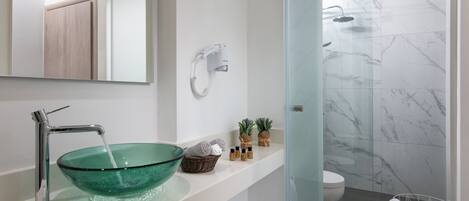 A modern bathroom with a glass bowl sink, a handheld showerhead, and a toilet.