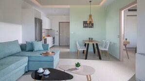 Una sala moderna con un sofá azul, una mesa de centro y un comedor con mesa y sillas.
