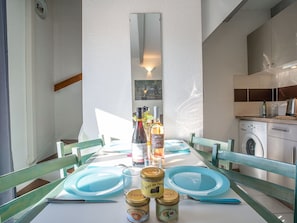 Una mesa de comedor dispuesta con platos azules, una botella de vino y frascos de paté.