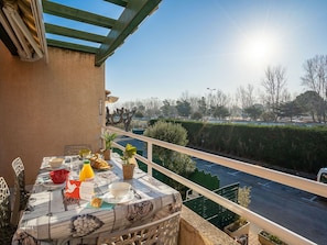 Un balcón con una mesa dispuesta para el desayuno, con vistas a una carretera y follaje.
