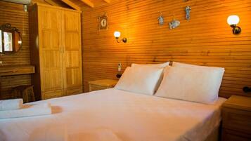 A wooden-paneled room with a bed, a nightstand, a wardrobe, and wall-mounted light fixtures.