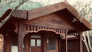Una cabaña de madera con un porche, un banco y una planta en maceta.