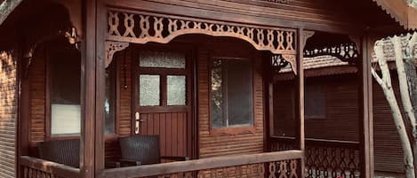 A wooden cabin with a porch, a bench, and a potted plant.