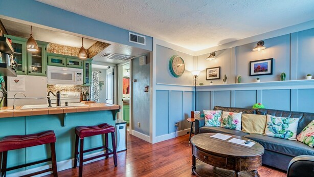 A cozy living room with a sofa, a coffee table, and a kitchen area with a bar.