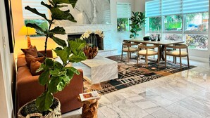 A modern living room with a fireplace, a dining area, and large windows. - Renzzi On The Beach (Miami Beach)