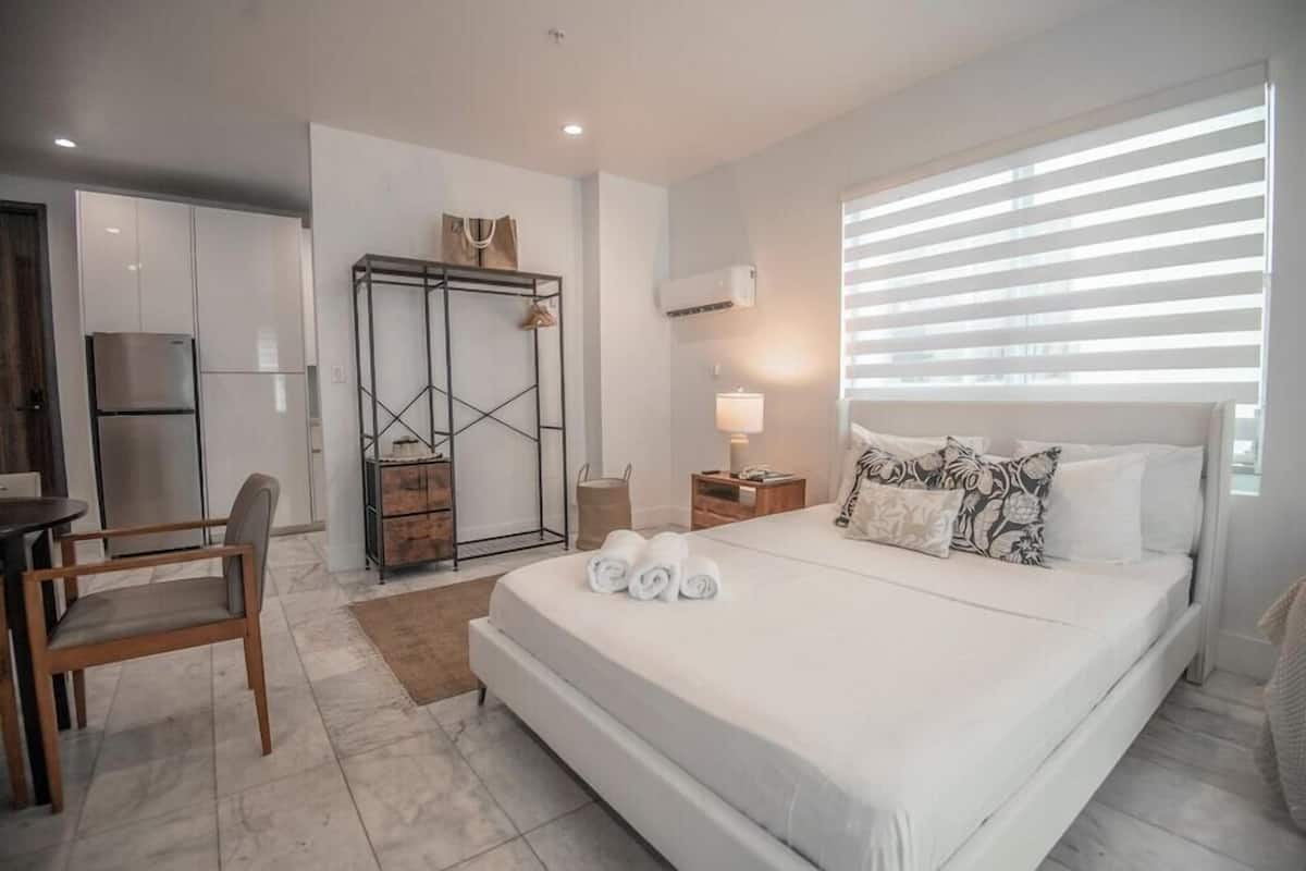 Un dormitorio con una cama, un escritorio, una silla, un armario y una ventana con persianas.
