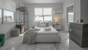 A modern bedroom with a large bed, a bedside table, a hanging shelf, and a view of the outdoors. - Renzzi On The Beach (Miami Beach)
