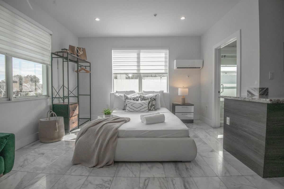 Un dormitorio moderno con una cama grande, una mesita de noche, un estante colgante y vistas al exterior.