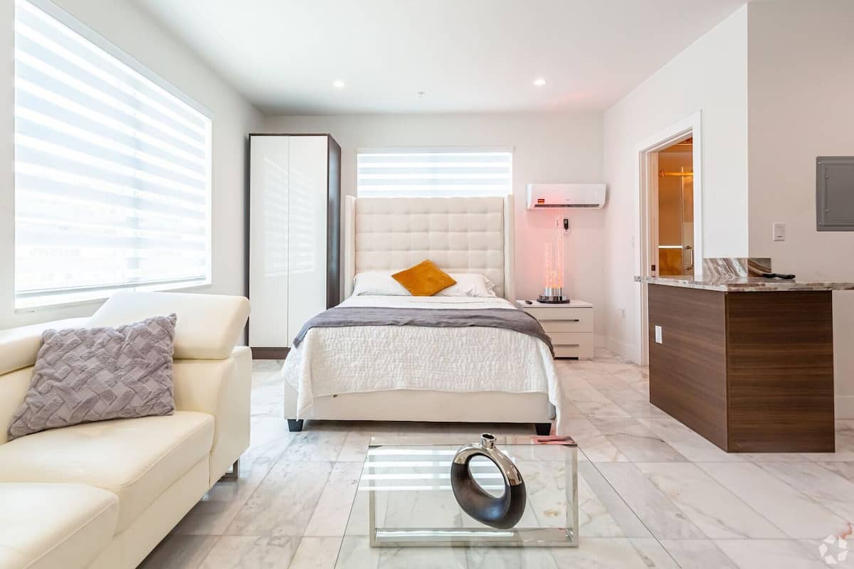 Un dormitorio moderno con cama, mesitas de noche, un sofá y un escritorio.