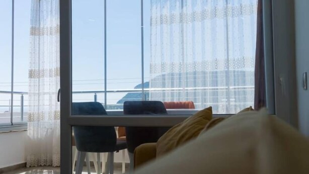 A room with a large window, a bed, and a table with chairs.