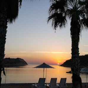 A sunset view with a beach, palm trees, and lounge chairs. - Tisan Apart (Silifke)