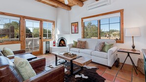 Un salón amplio con chimenea, ventanas grandes y ventilador de techo.
