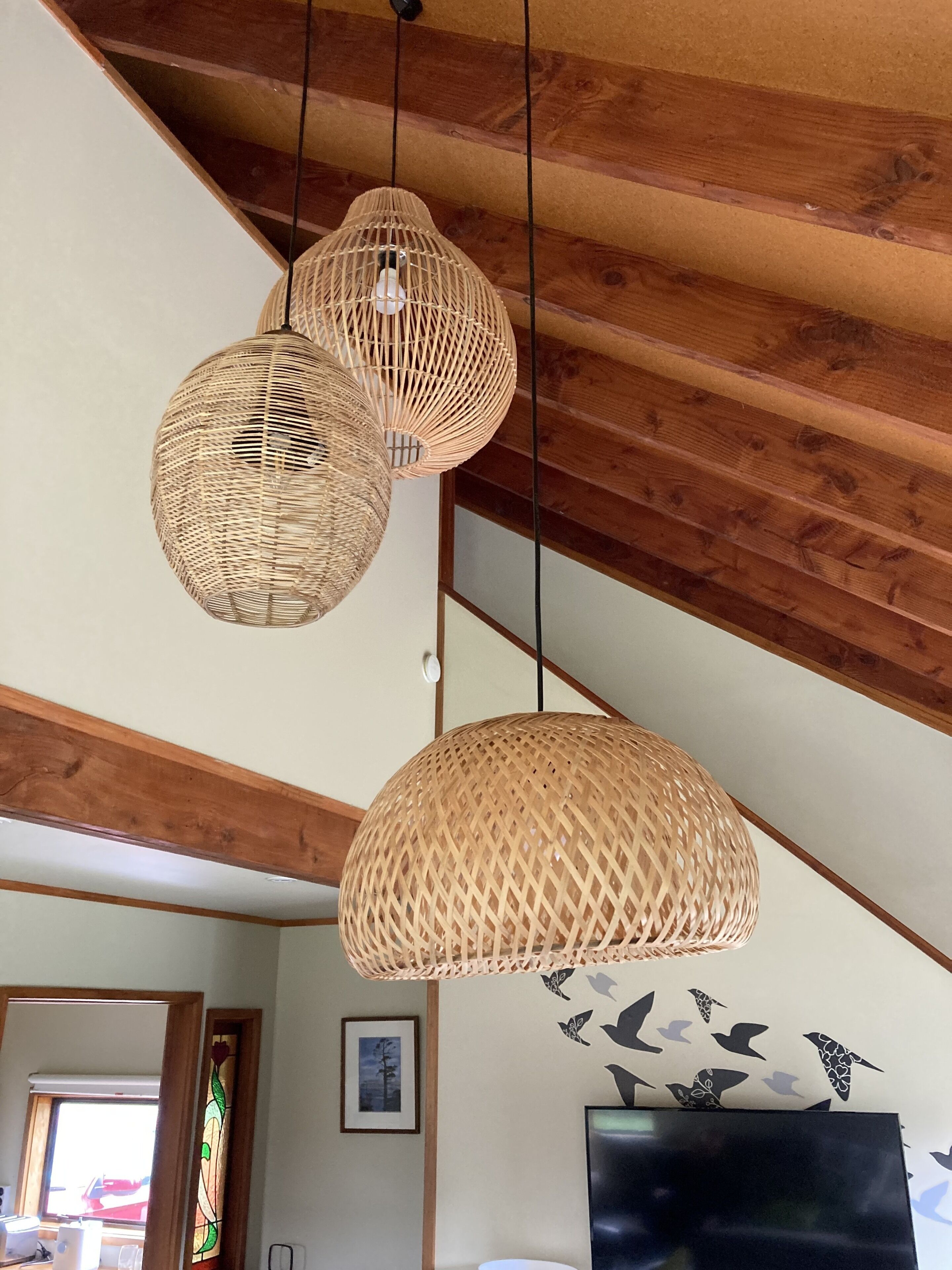 Ein Zimmer mit Holzbalken, einem großen Flachbildfernseher und einer Wand mit Vogelmotiven.