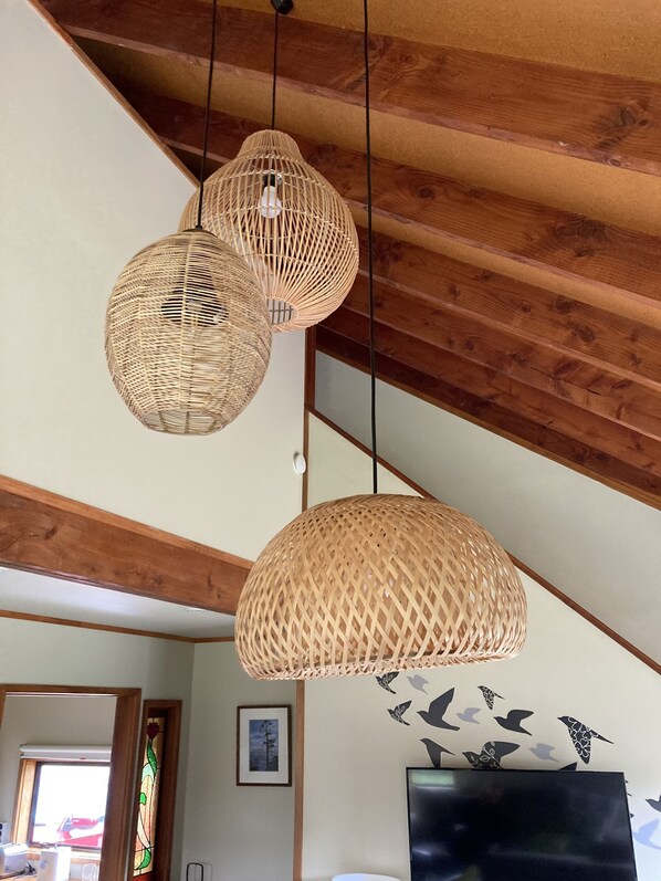 A room with wooden ceiling beams, a large flat-screen TV, and a wall with bird decals.